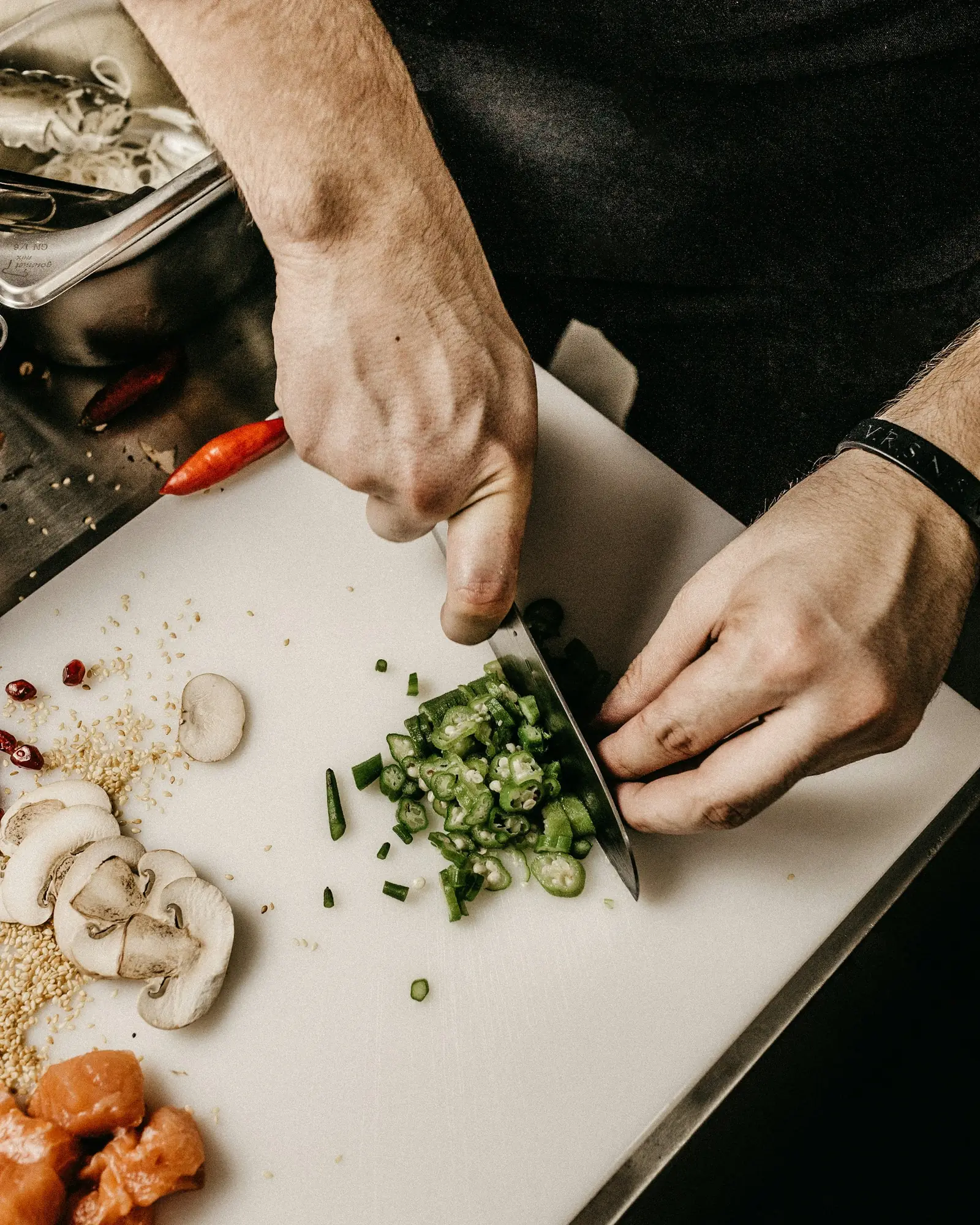 A chef's hands finishing a dish with fresh herbs