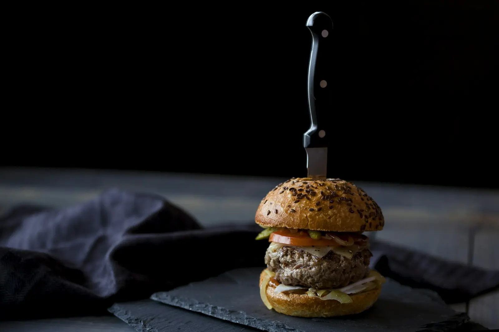 A small burger on a dark slate board