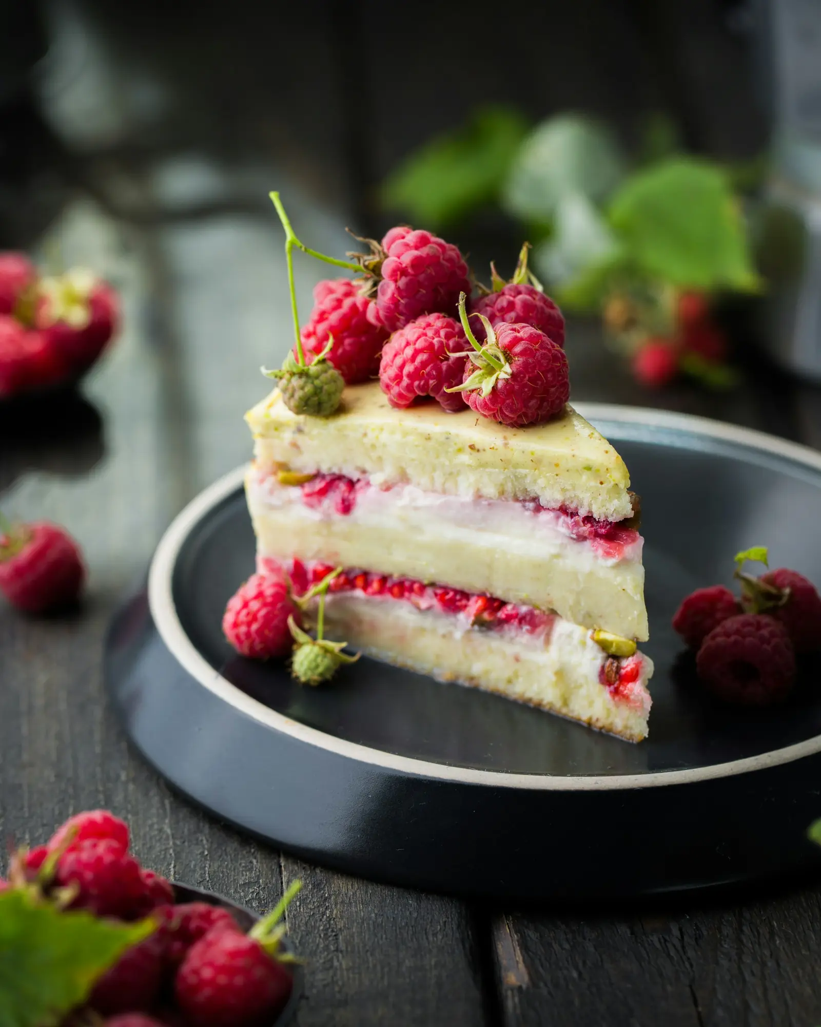 A slice of layered raspberry cake on a dark plate