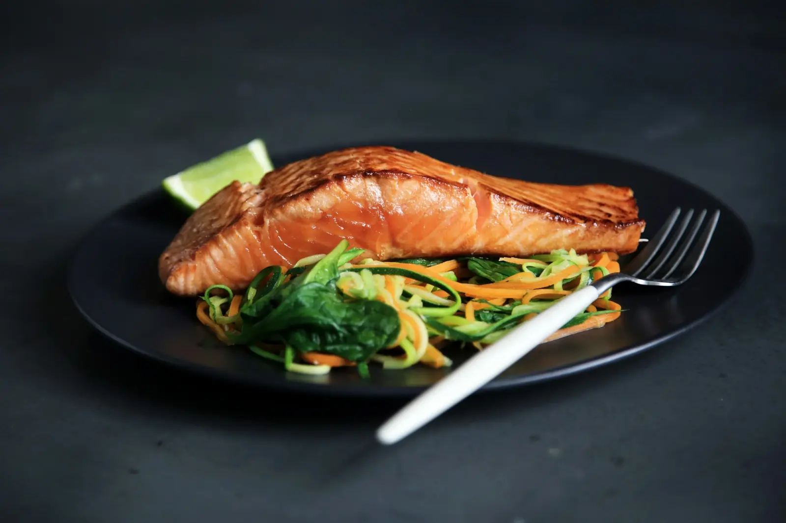 Seared salmon with greens on a black plate