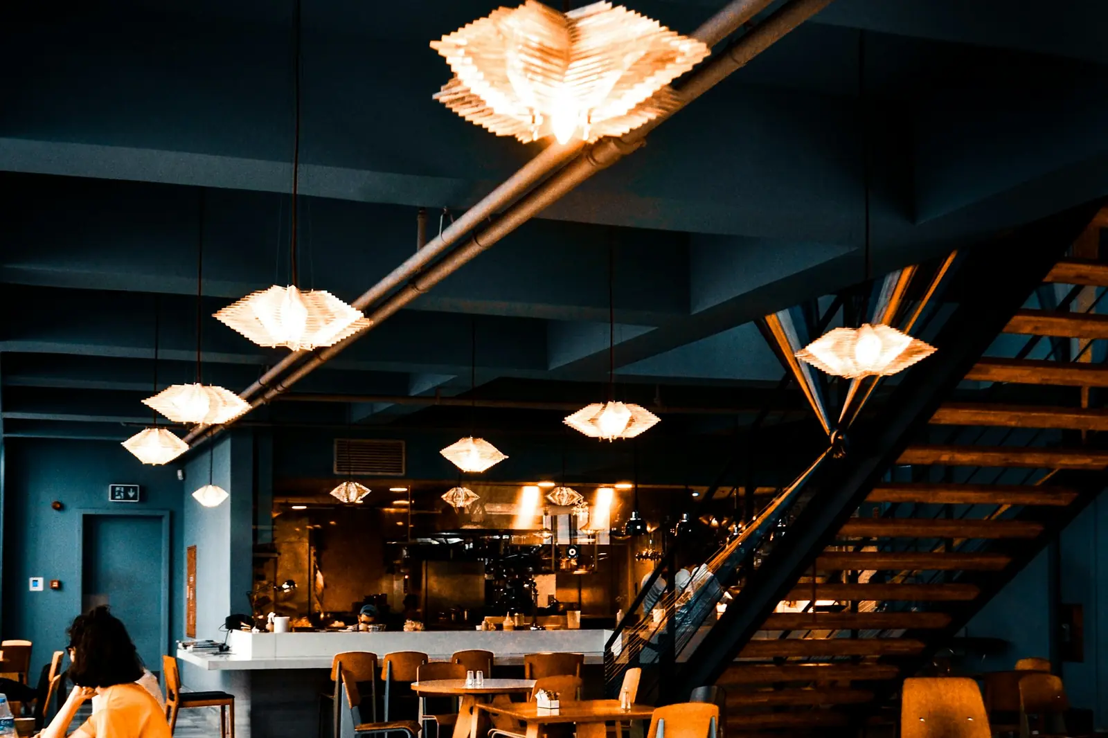 A dark dining room lit by warm pendant lamps