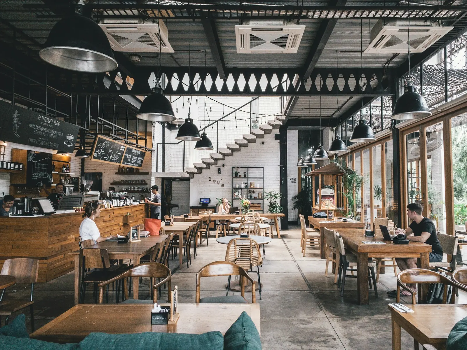 Airy dining hall with industrial beams and tall windows